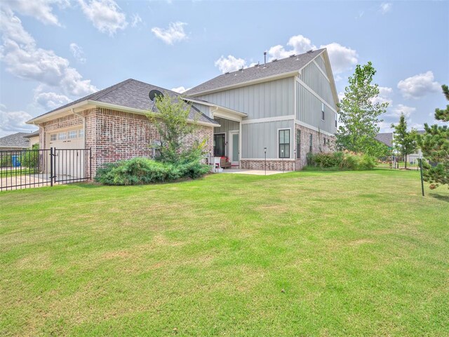 back of property featuring a lawn and a garage