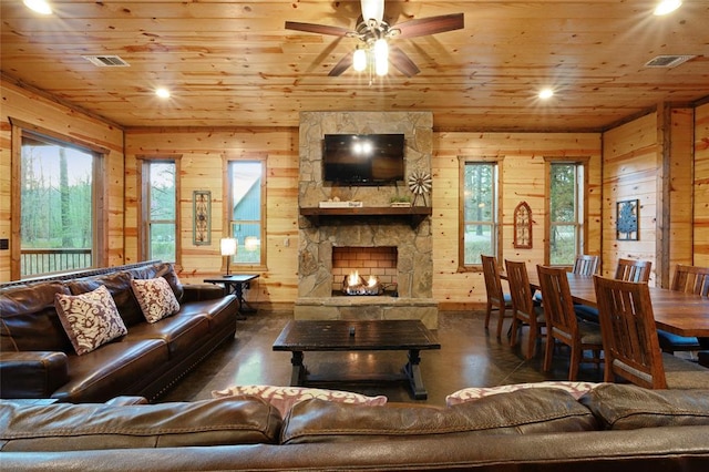 living room with a stone fireplace, ceiling fan, wood walls, and wood ceiling