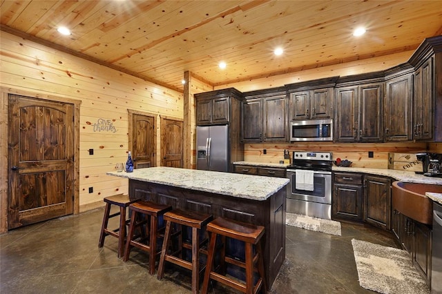 kitchen with appliances with stainless steel finishes, light stone counters, wood ceiling, dark brown cabinetry, and a center island