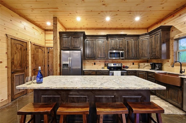178 Black Jack Trl, Broken Bow, OK 74728 - kitchen featuring stainless steel appliances, wood walls, wood ceiling, dark brown cabinets, and a breakfast bar area