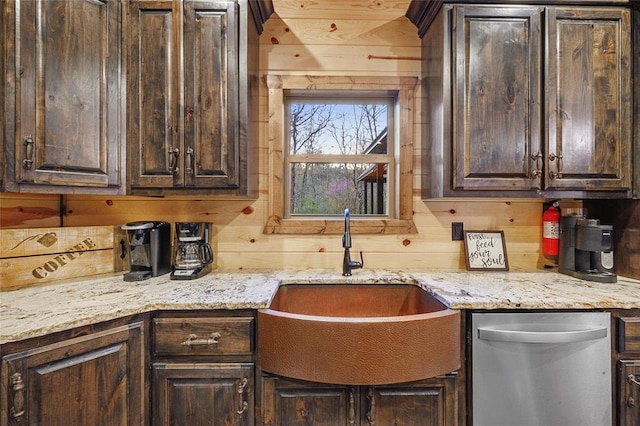 kitchen featuring dishwasher, dark brown cabinets, sink, and wood walls