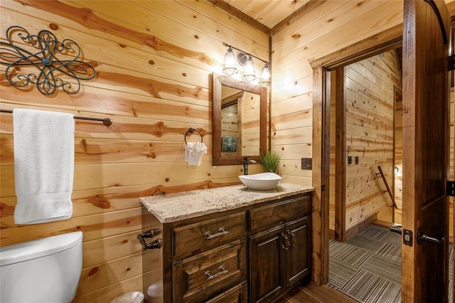 bathroom with vanity, toilet, and wooden walls