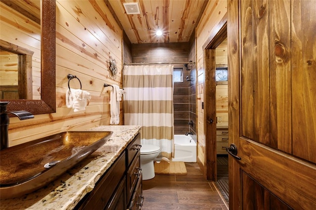 full bathroom with vanity, hardwood / wood-style flooring, shower / bathtub combination with curtain, toilet, and wood walls