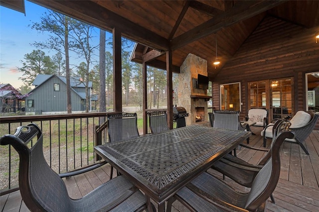 deck at dusk with an outdoor stone fireplace and a grill