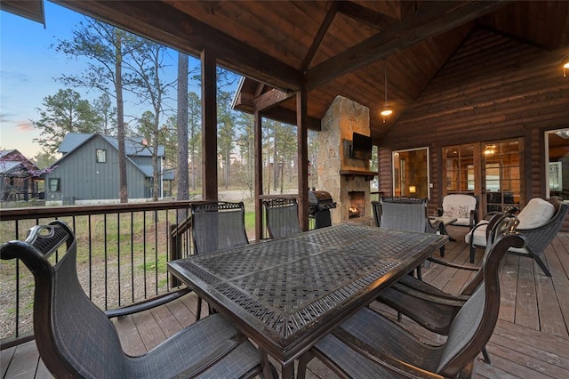 178 Black Jack Trl, Broken Bow, OK 74728 - deck at dusk featuring an outdoor stone fireplace, outdoor dining space, and grilling area
