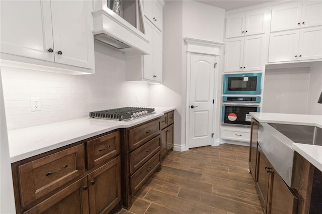 kitchen with stainless steel appliances, premium range hood, white cabinets, and decorative backsplash