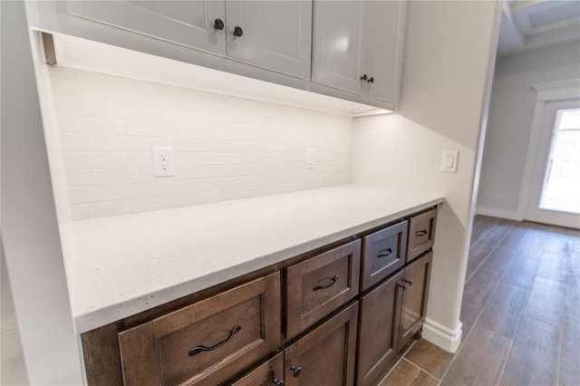 bar featuring tasteful backsplash, dark brown cabinets, and light hardwood / wood-style floors