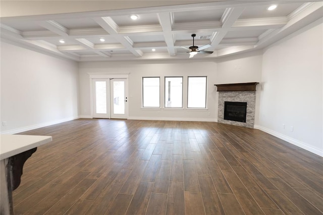 unfurnished living room with dark wood-type flooring, ceiling fan, coffered ceiling, a fireplace, and beamed ceiling