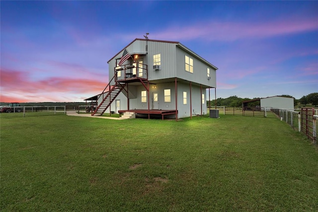 rear view of house with stairs, a lawn, and fence