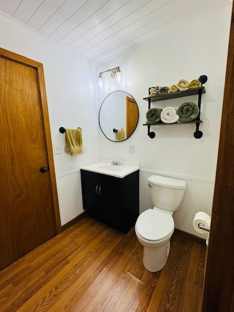 bathroom with toilet, wooden ceiling, wood finished floors, and vanity