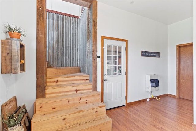 stairway featuring heating unit, baseboards, and wood finished floors