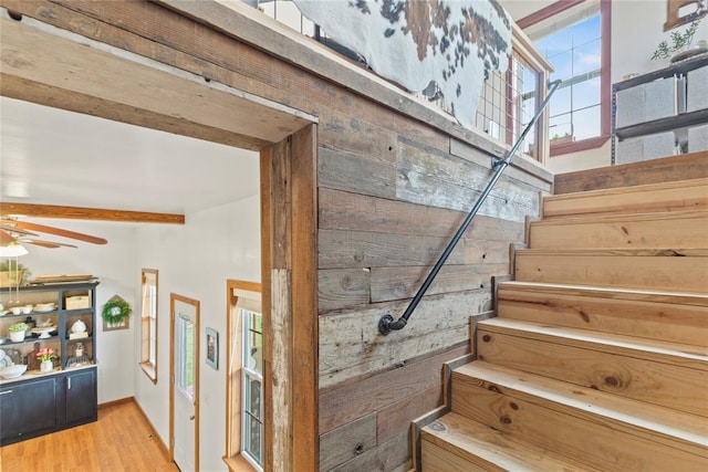 staircase featuring ceiling fan, wood finished floors, and beam ceiling