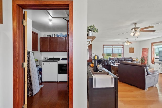 kitchen featuring washer and clothes dryer, visible vents, light wood-style flooring, open floor plan, and dark brown cabinets