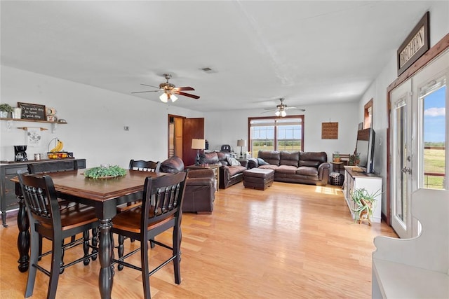 dining room with light wood finished floors, visible vents, and a ceiling fan