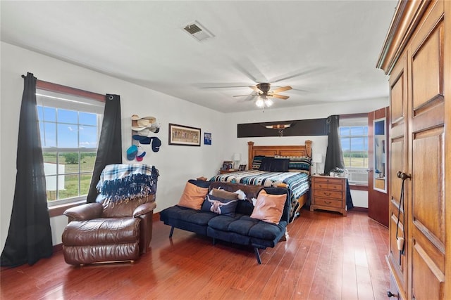 bedroom with a ceiling fan, multiple windows, visible vents, and dark wood-type flooring