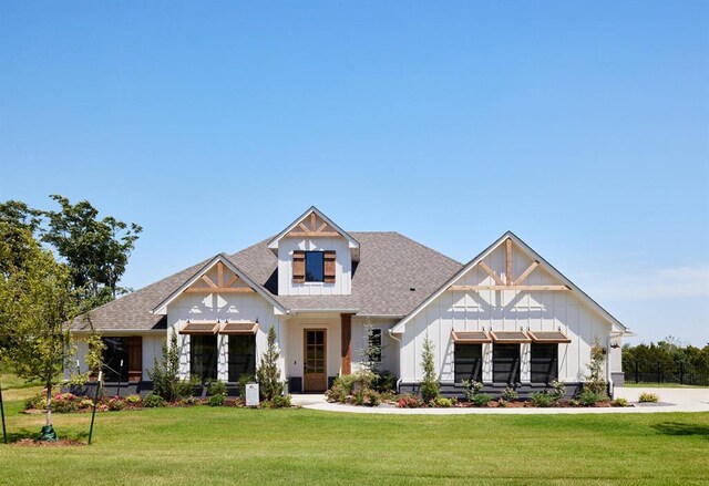 view of front facade with a shingled roof, board and batten siding, and a front yard