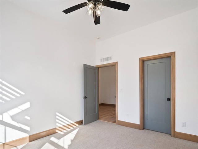 unfurnished bedroom featuring light carpet, ceiling fan, visible vents, and baseboards