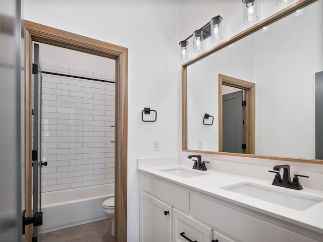 bathroom featuring double vanity, tile patterned flooring, toilet, and a sink