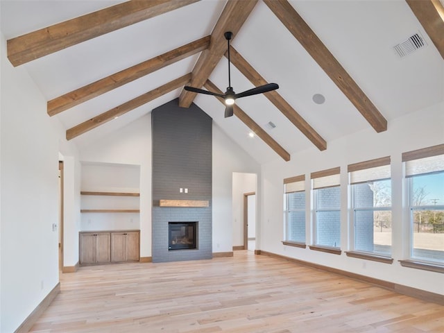 unfurnished living room featuring a healthy amount of sunlight, high vaulted ceiling, a brick fireplace, and visible vents