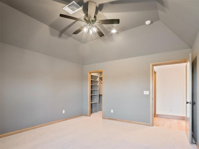 spare room with lofted ceiling, baseboards, visible vents, and light colored carpet