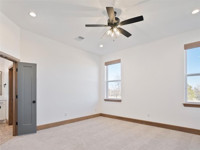 empty room with baseboards, visible vents, a wealth of natural light, and light colored carpet