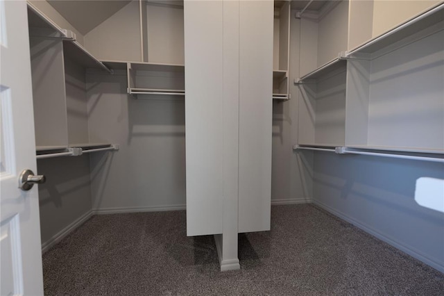 spacious closet with dark colored carpet and vaulted ceiling