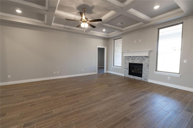 unfurnished living room with ceiling fan, coffered ceiling, a stone fireplace, and a wealth of natural light