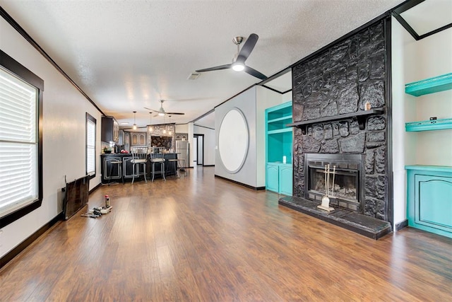 667 County Road 1410th Rd, Ninnekah, OK 73067 - living area with a ceiling fan, wood finished floors, a stone fireplace, built in shelves, and baseboards