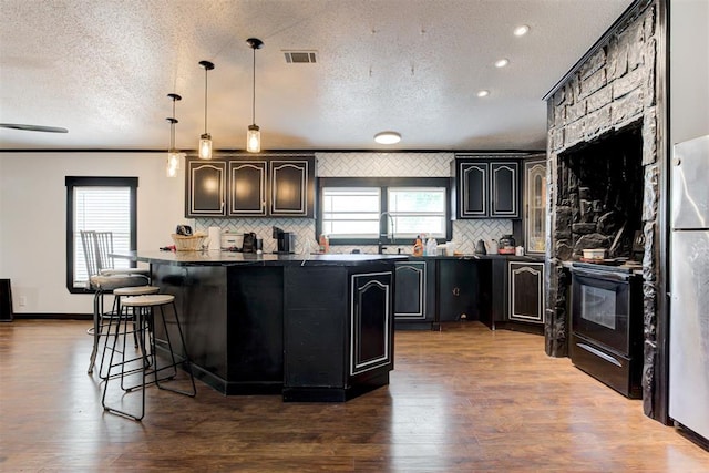 667 County Road 1410th Rd, Ninnekah, OK 73067 - kitchen featuring dark countertops, electric range, backsplash, a textured ceiling, and a kitchen bar