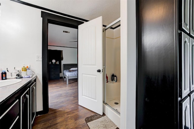 667 County Road 1410th Rd, Ninnekah, OK 73067 - ensuite bathroom featuring a shower stall, wood finished floors, vanity, and a textured ceiling