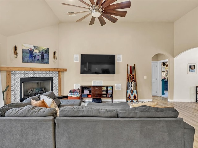 living room with ceiling fan, lofted ceiling, a fireplace, and light hardwood / wood-style flooring