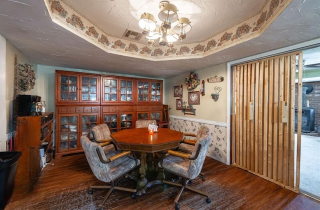 dining space with a chandelier, dark hardwood / wood-style flooring, a textured ceiling, and a tray ceiling