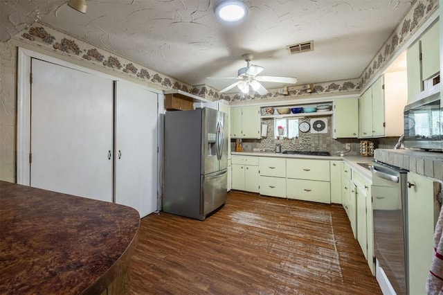 kitchen with dark hardwood / wood-style floors, ceiling fan, stainless steel appliances, and tasteful backsplash