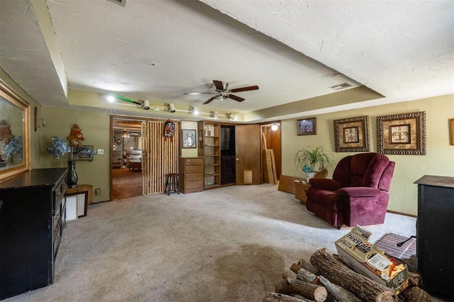 living room featuring ceiling fan, light colored carpet, and a tray ceiling