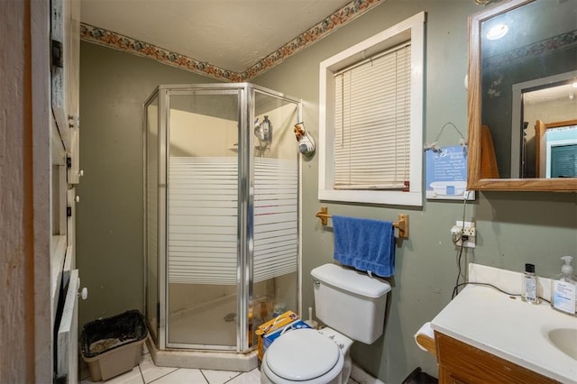 bathroom featuring tile patterned floors, vanity, toilet, and a shower with shower door