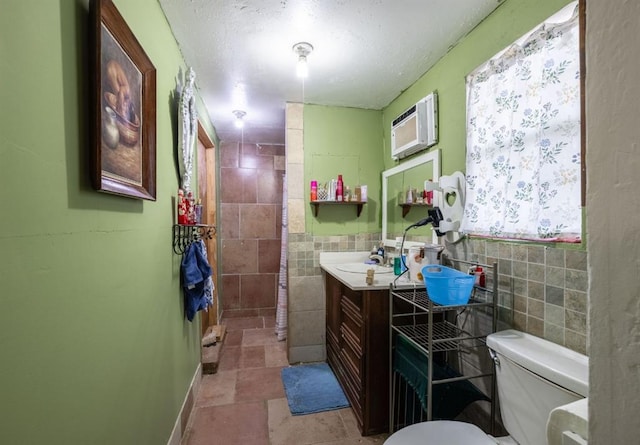 bathroom featuring a wall mounted AC, vanity, toilet, and tile walls