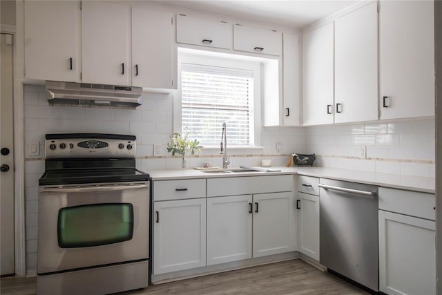 kitchen with stainless steel appliances, white cabinetry, light hardwood / wood-style floors, and sink