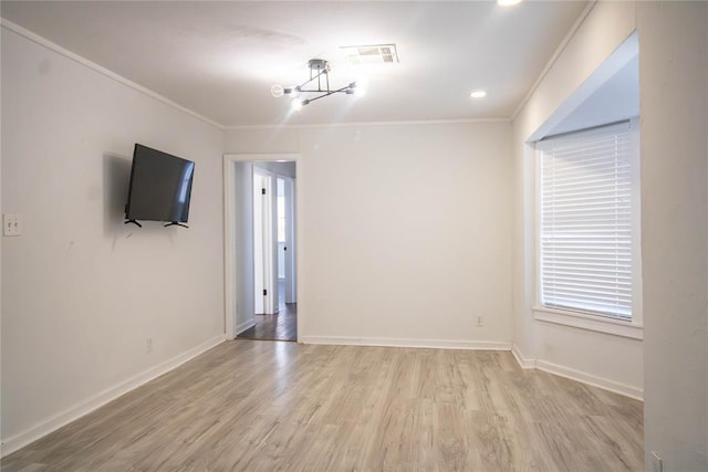 spare room featuring light wood-type flooring, crown molding, and an inviting chandelier