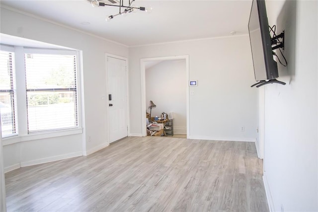 empty room featuring light hardwood / wood-style flooring, crown molding, and a notable chandelier