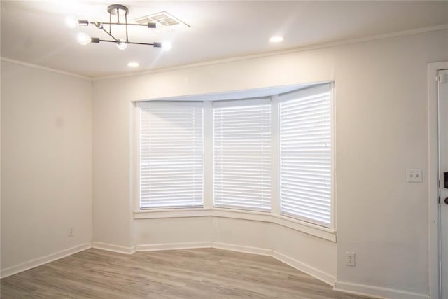 empty room with wood-type flooring, an inviting chandelier, and ornamental molding