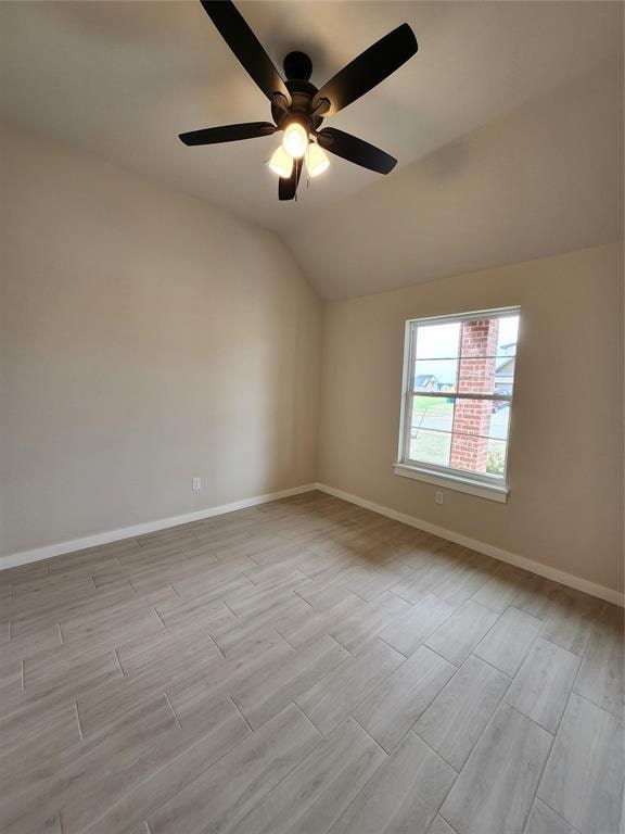 spare room featuring ceiling fan, light wood-type flooring, and vaulted ceiling