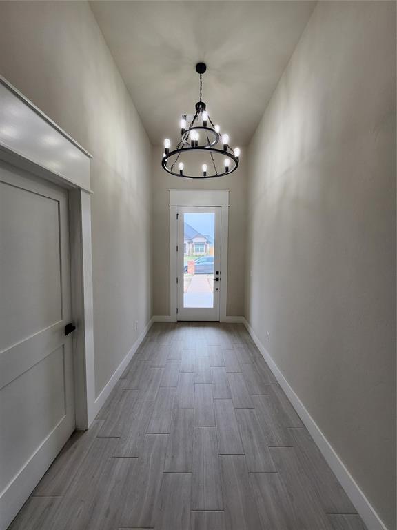 9320 SW 34th St, Oklahoma City, OK 73179 - doorway to outside featuring a chandelier, wood finished floors, and baseboards