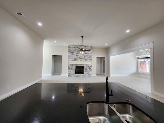 kitchen featuring a stone fireplace, ceiling fan, and sink