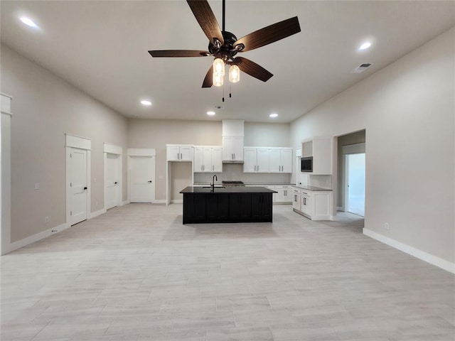 kitchen featuring ceiling fan, sink, white cabinetry, and a kitchen island with sink