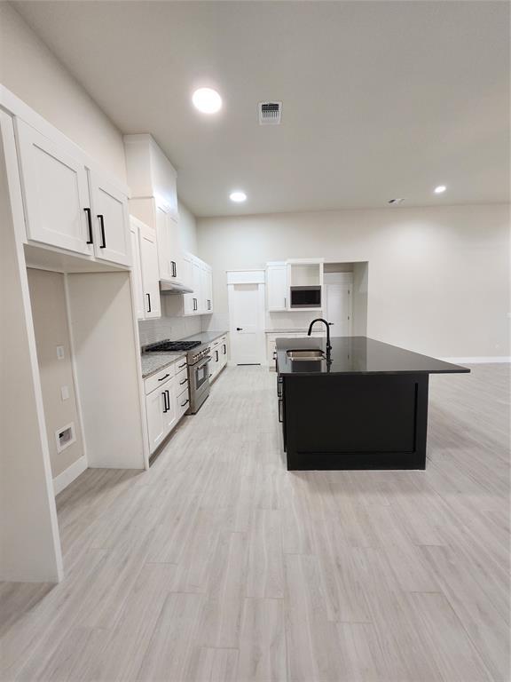 9320 SW 34th St, Oklahoma City, OK 73179 - kitchen with high end stainless steel range, a sink, white cabinetry, open shelves, and baseboards