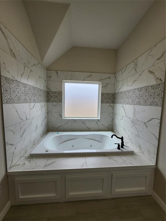 bathroom featuring a bath and vaulted ceiling