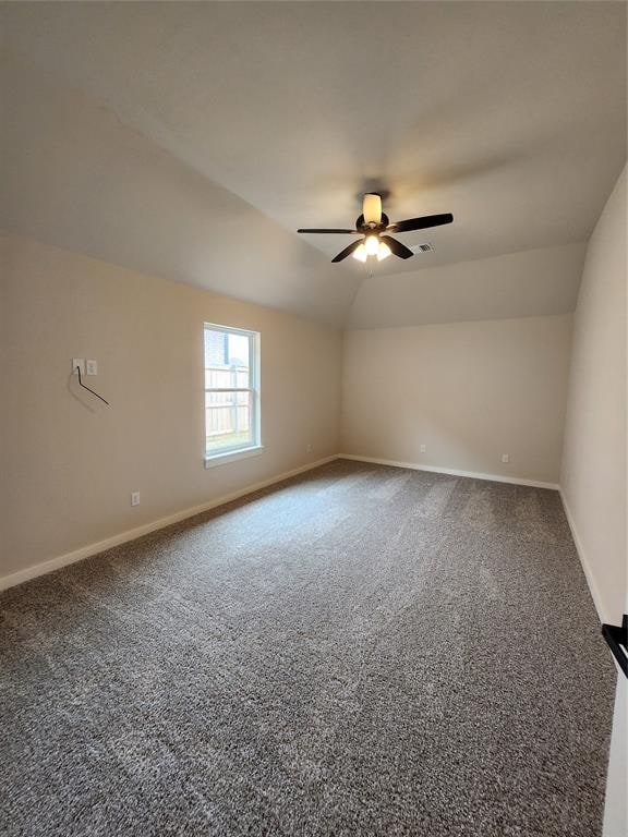 carpeted empty room with ceiling fan and lofted ceiling