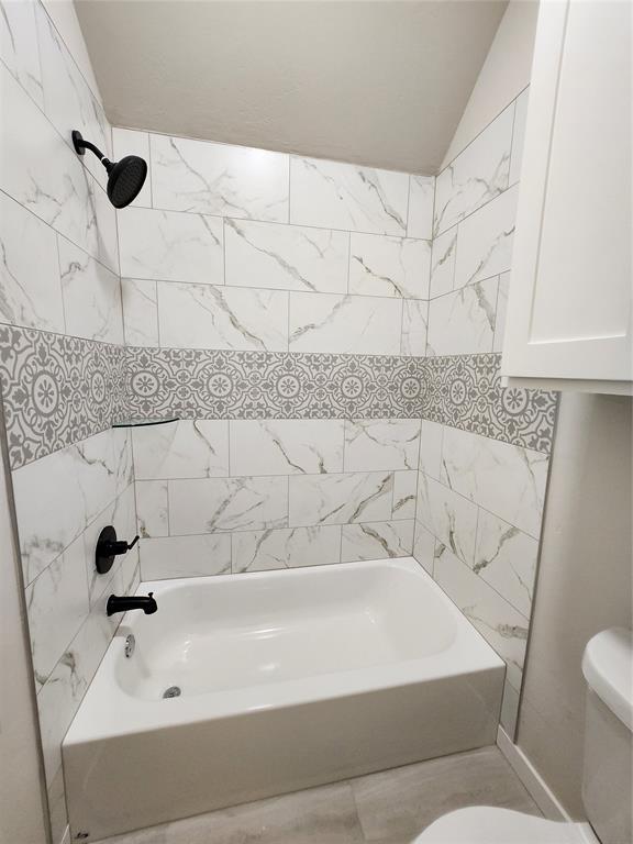 9320 SW 34th St, Oklahoma City, OK 73179 - bathroom featuring toilet, tub / shower combination, and vaulted ceiling