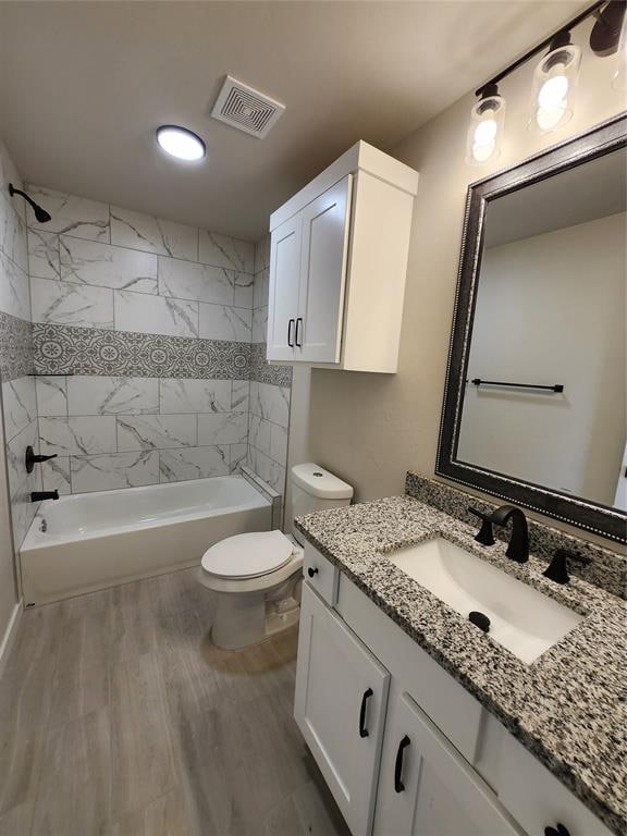 full bathroom featuring tiled shower / bath, toilet, vanity, and hardwood / wood-style flooring