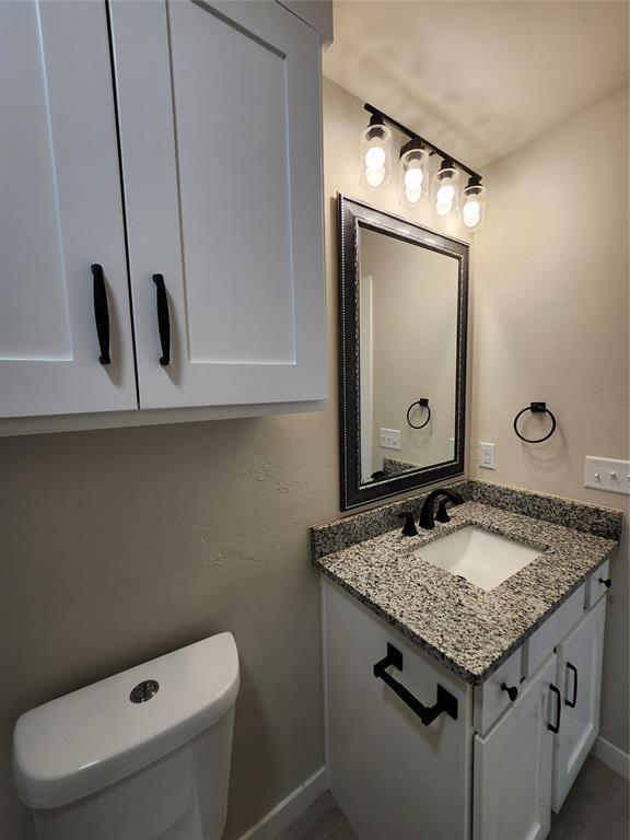 9320 SW 34th St, Oklahoma City, OK 73179 - half bath with vanity, baseboards, toilet, and wood finished floors